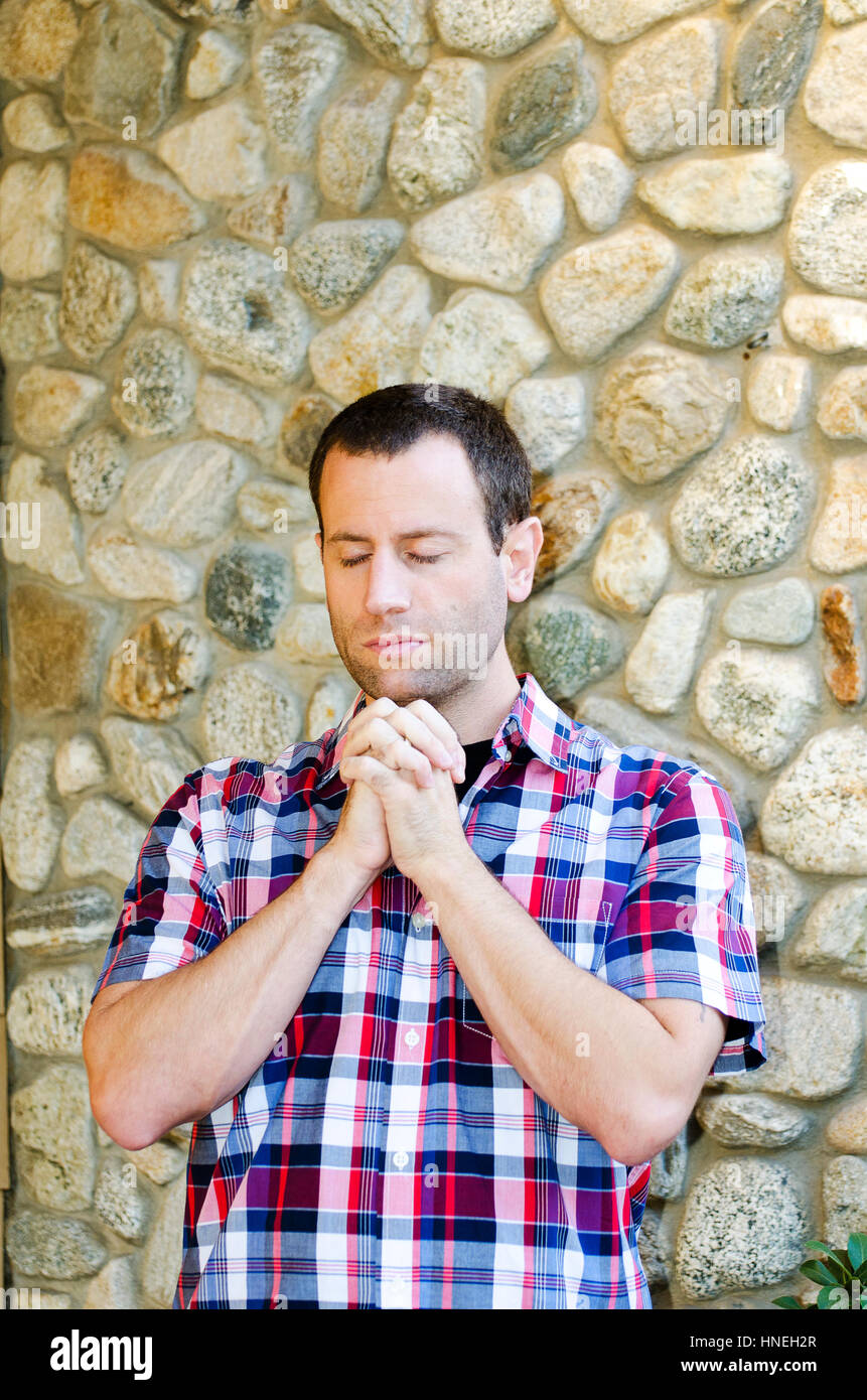 Man praying alone with hands clasped together. Stock Photo