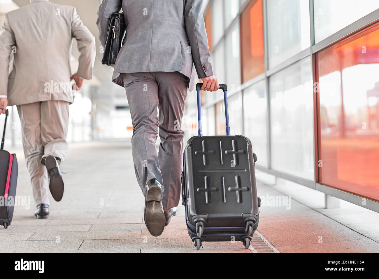 Rear view of businessmen with luggage running on railroad platform Stock Photo