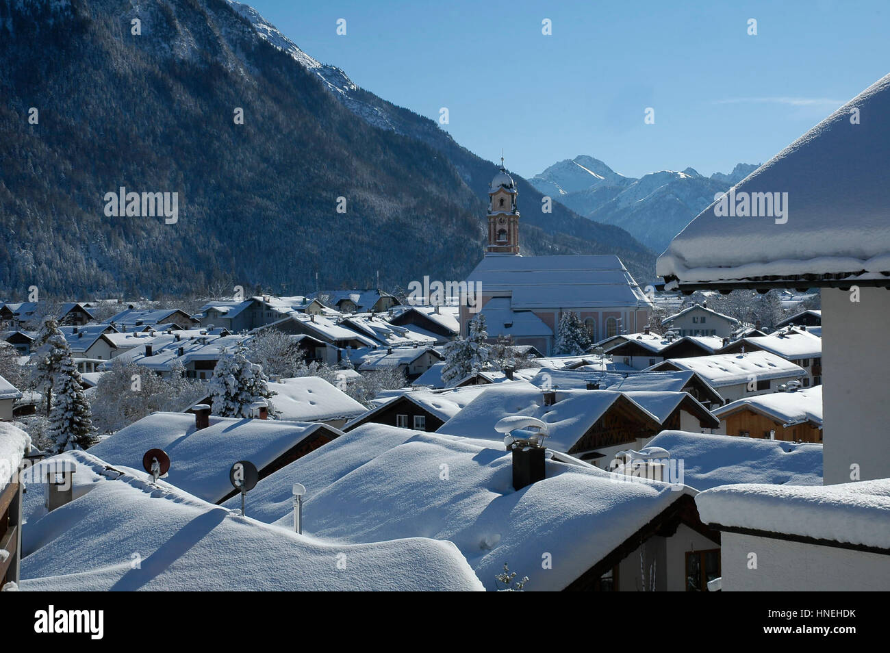 View of scenic winter landscape in the Bavarian Alps with famous St.Peter and Paul church in Mittenwald city Upper Bavaria, Germany. A lot of Snow. Stock Photo