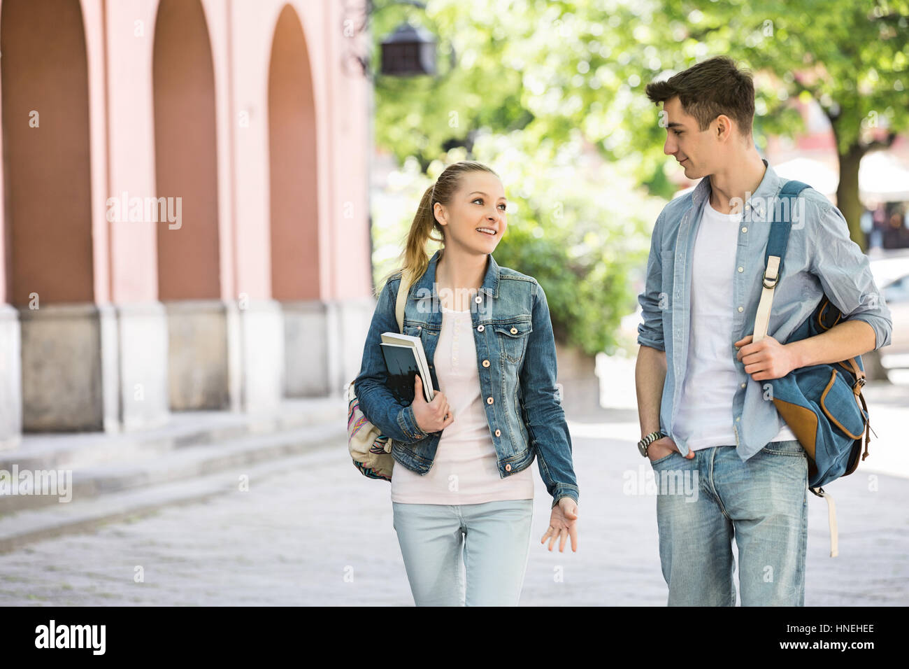 Young college friends talking while walking at campus Stock Photo
