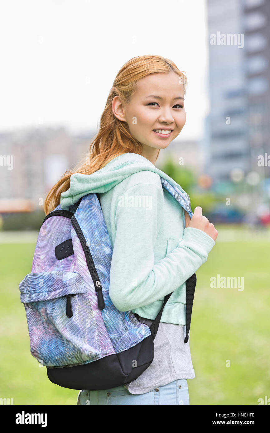 Portrait of happy young woman with backpack at college campus Stock