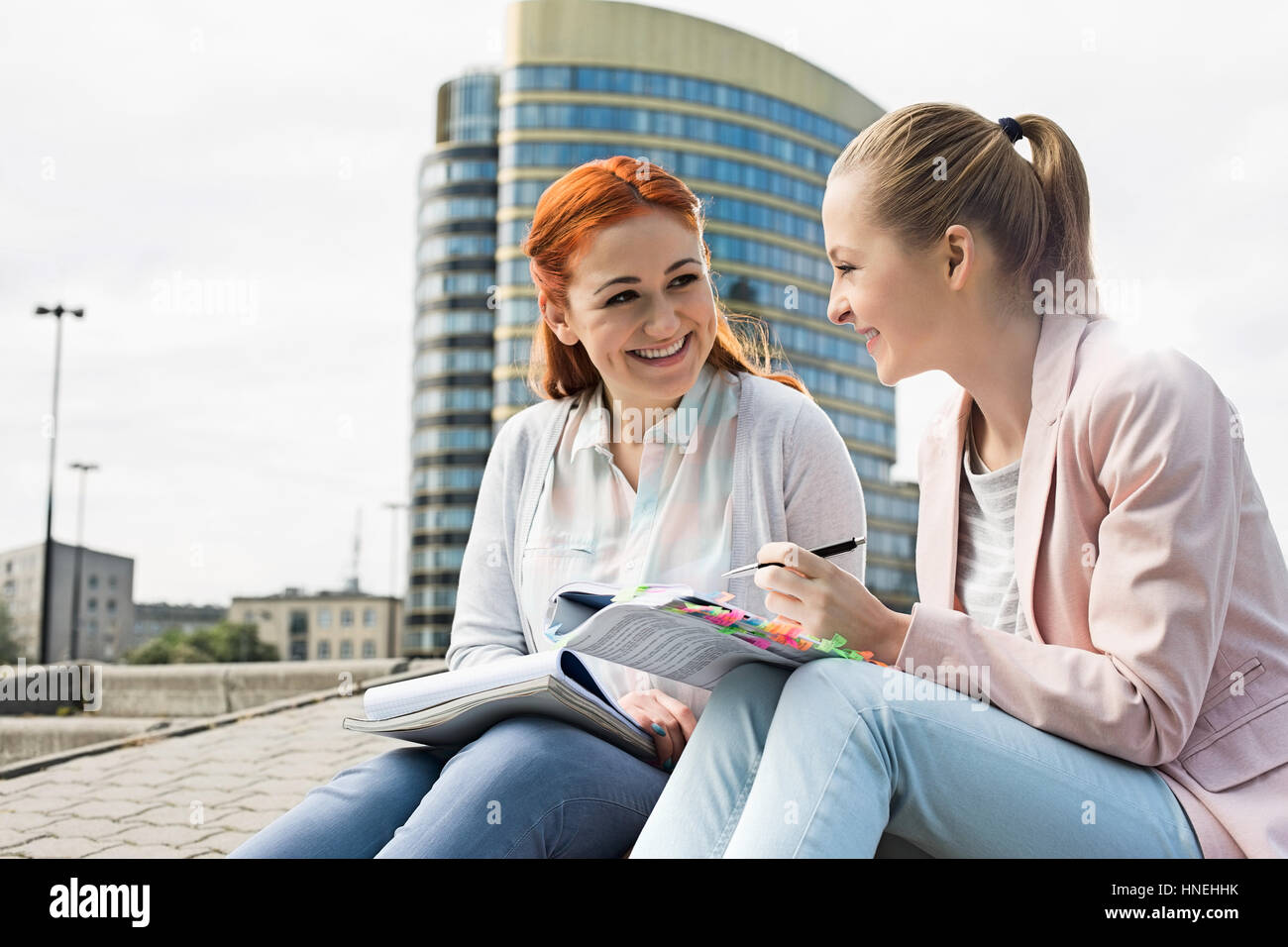 Smiling young university students studying against building Stock Photo