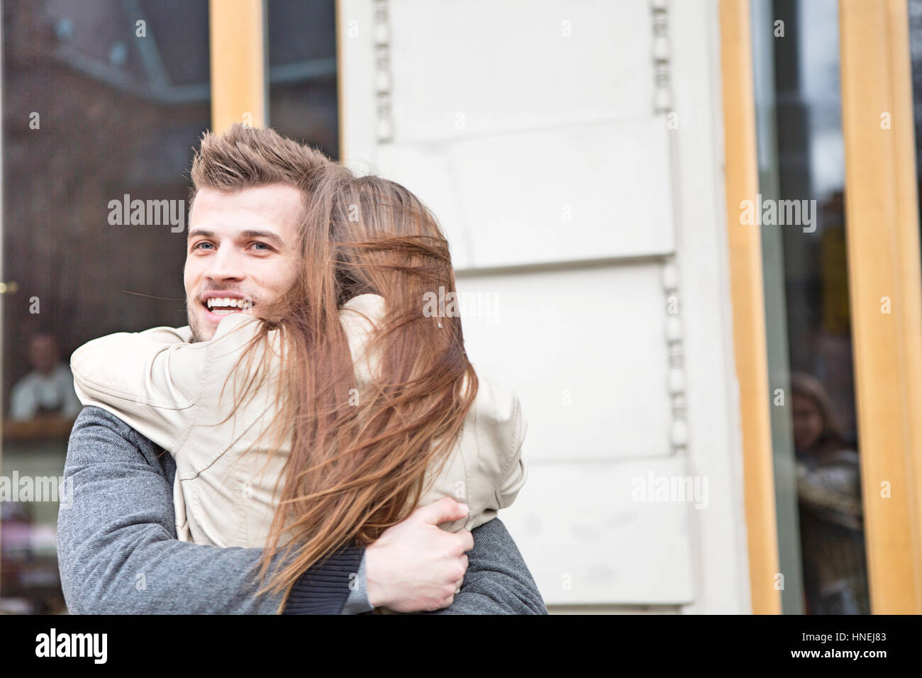 Happy young man hugging woman outside cafe Stock Photo - Alamy