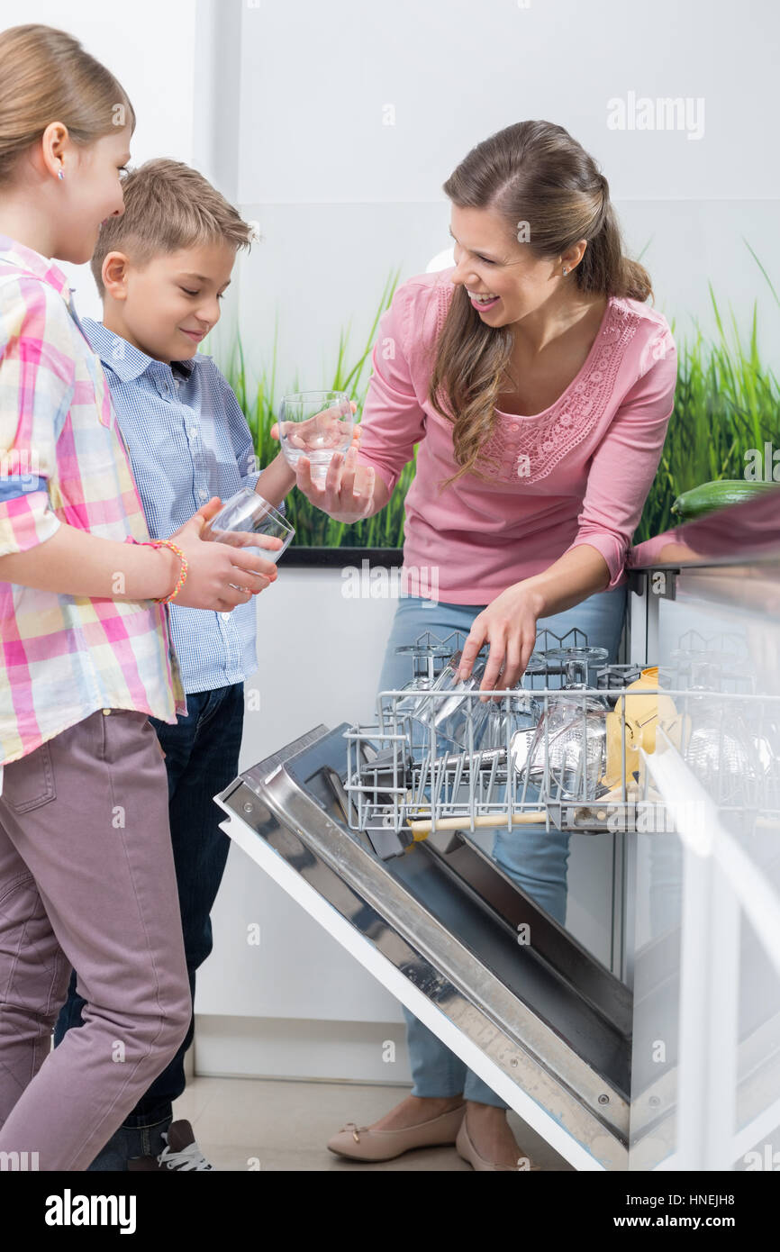 Happy mother and children placing glasses in dishwasher Stock Photo Alamy