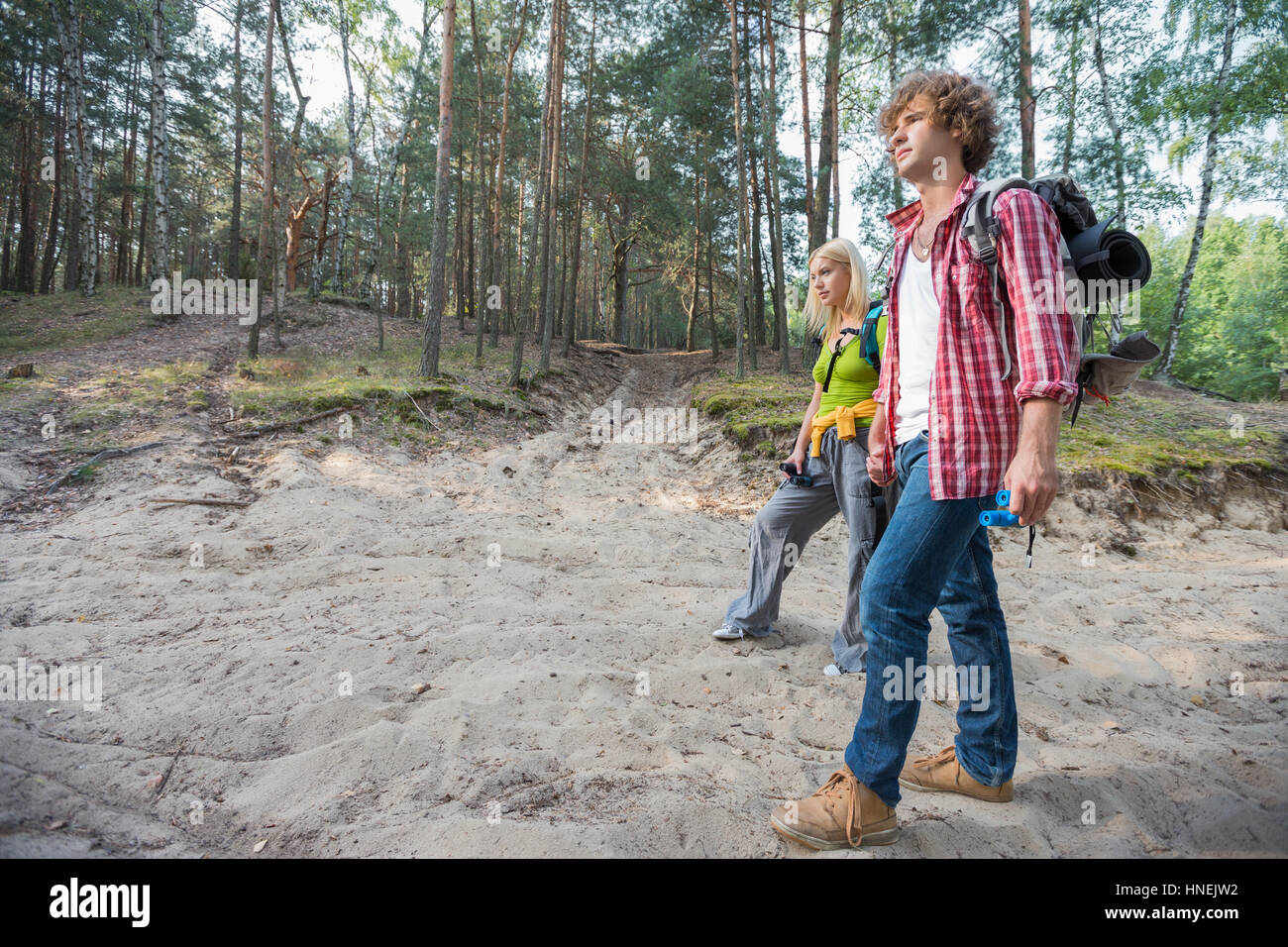 Full length of hiking couple walking in forest Stock Photo