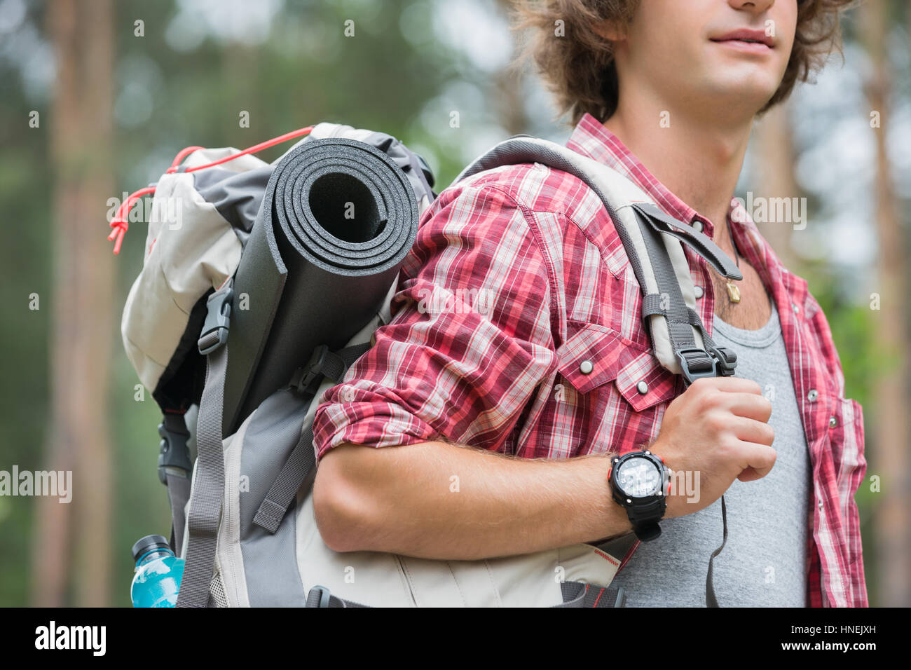 Midsection of male hiker carrying backpack in forest Stock Photo