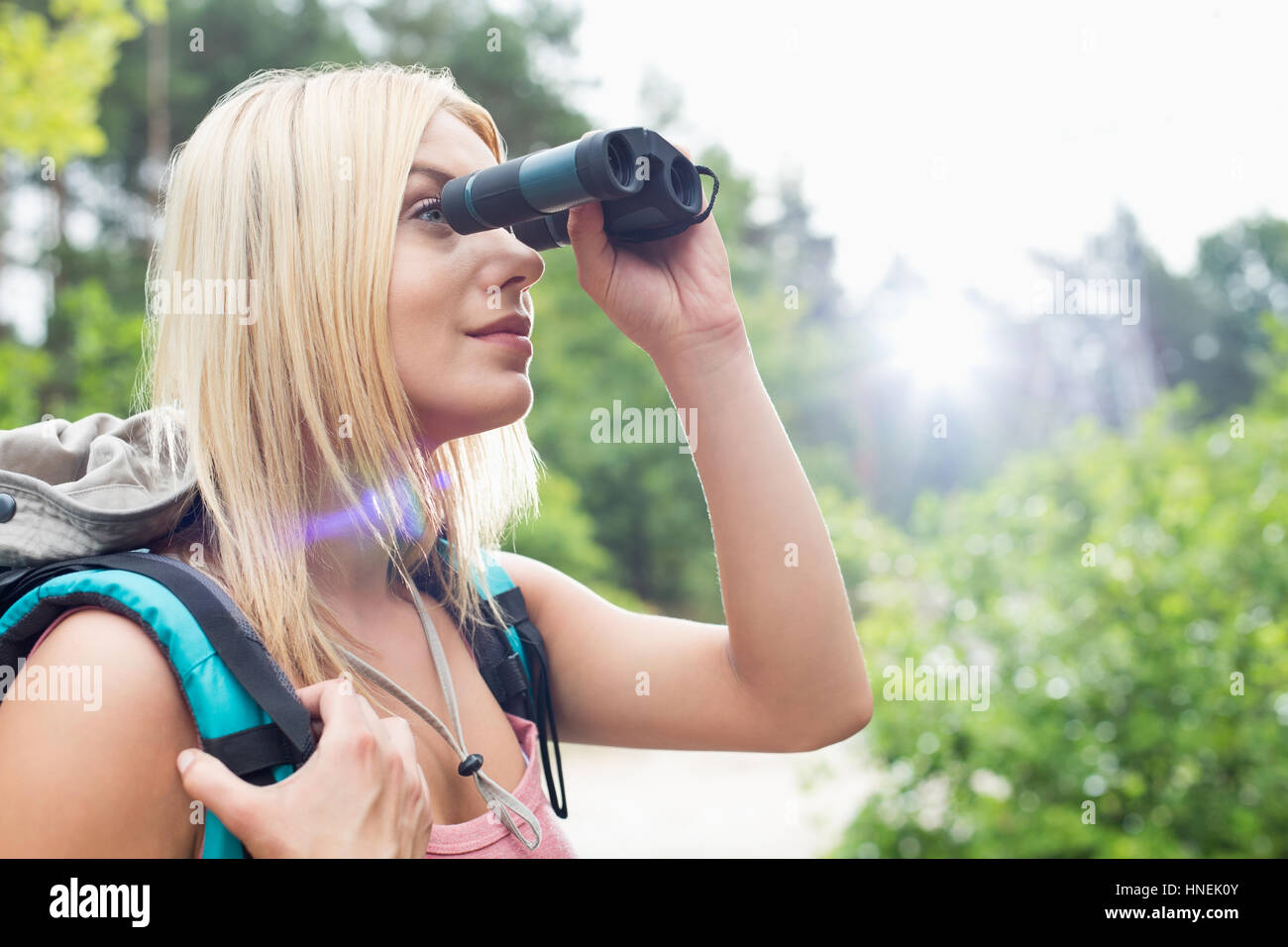 Young female hiker using binoculars in forest Stock Photo