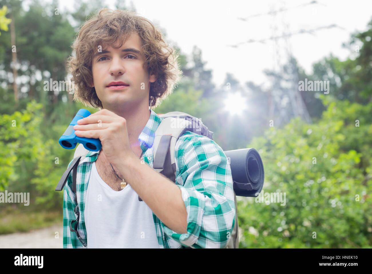 Young male hiker with binoculars in forest Stock Photo