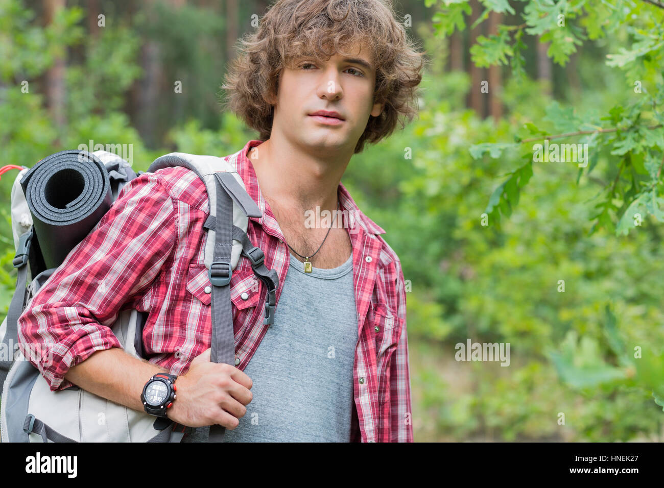 Young male hiker with backpack looking away in forest Stock Photo