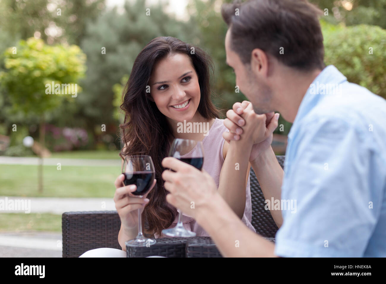 Romantic young couple having red wine in park Stock Photo - Alamy