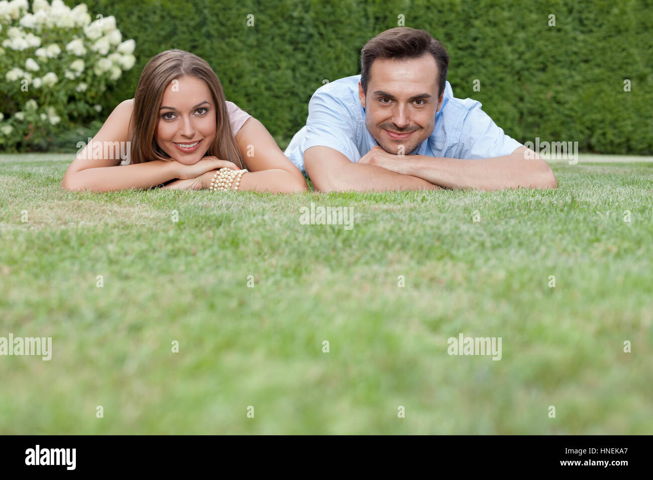 Portrait of smiling young couple relaxing on grass in park Stock Photo ...