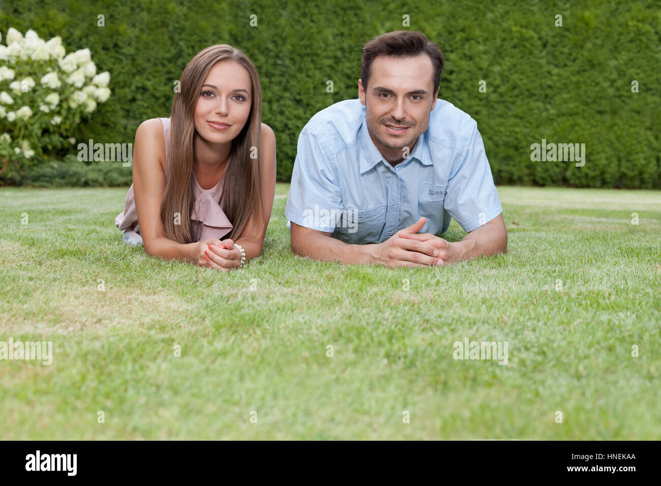 Portrait of happy young couple lying on grass in park Stock Photo - Alamy