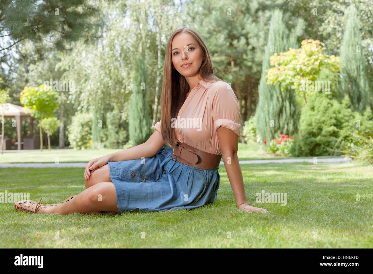 Portrait of attractive young woman sitting on grass in park Stock Photo ...