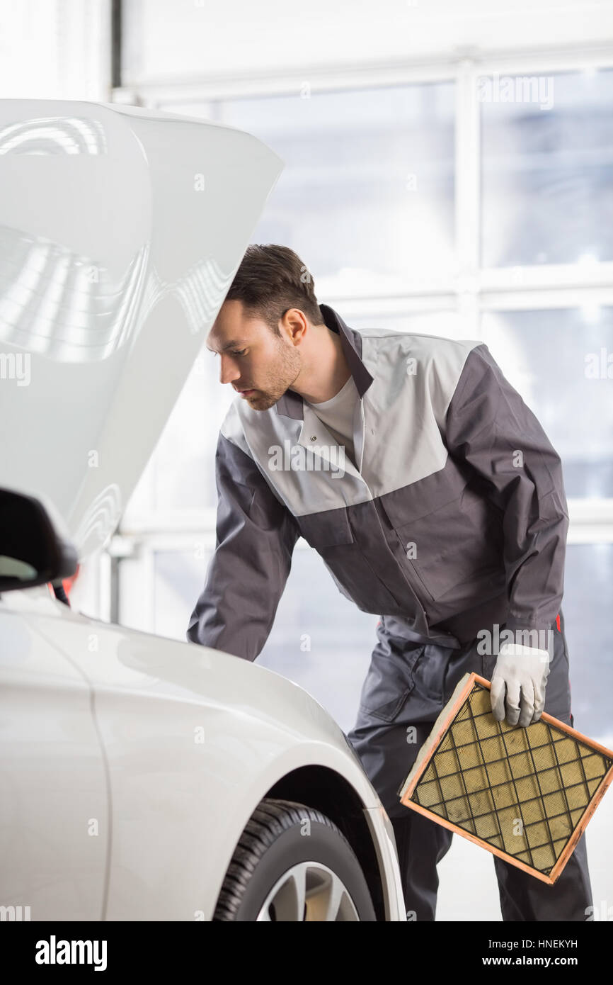 Young automobile mechanic examining car in automobile shop Stock Photo