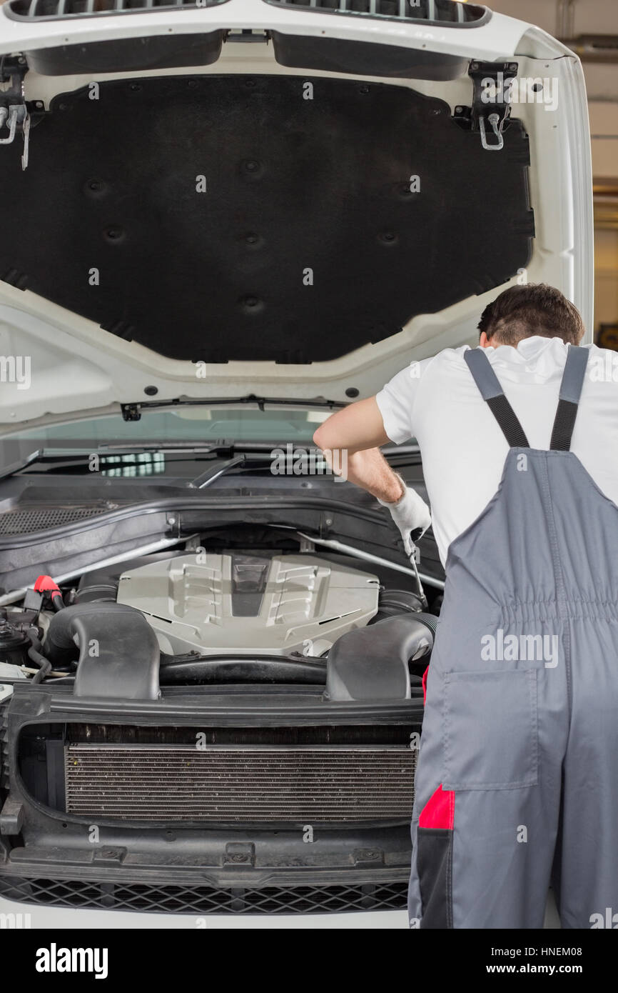 Rear view of male engineer repairing car in automobile repair shop ...