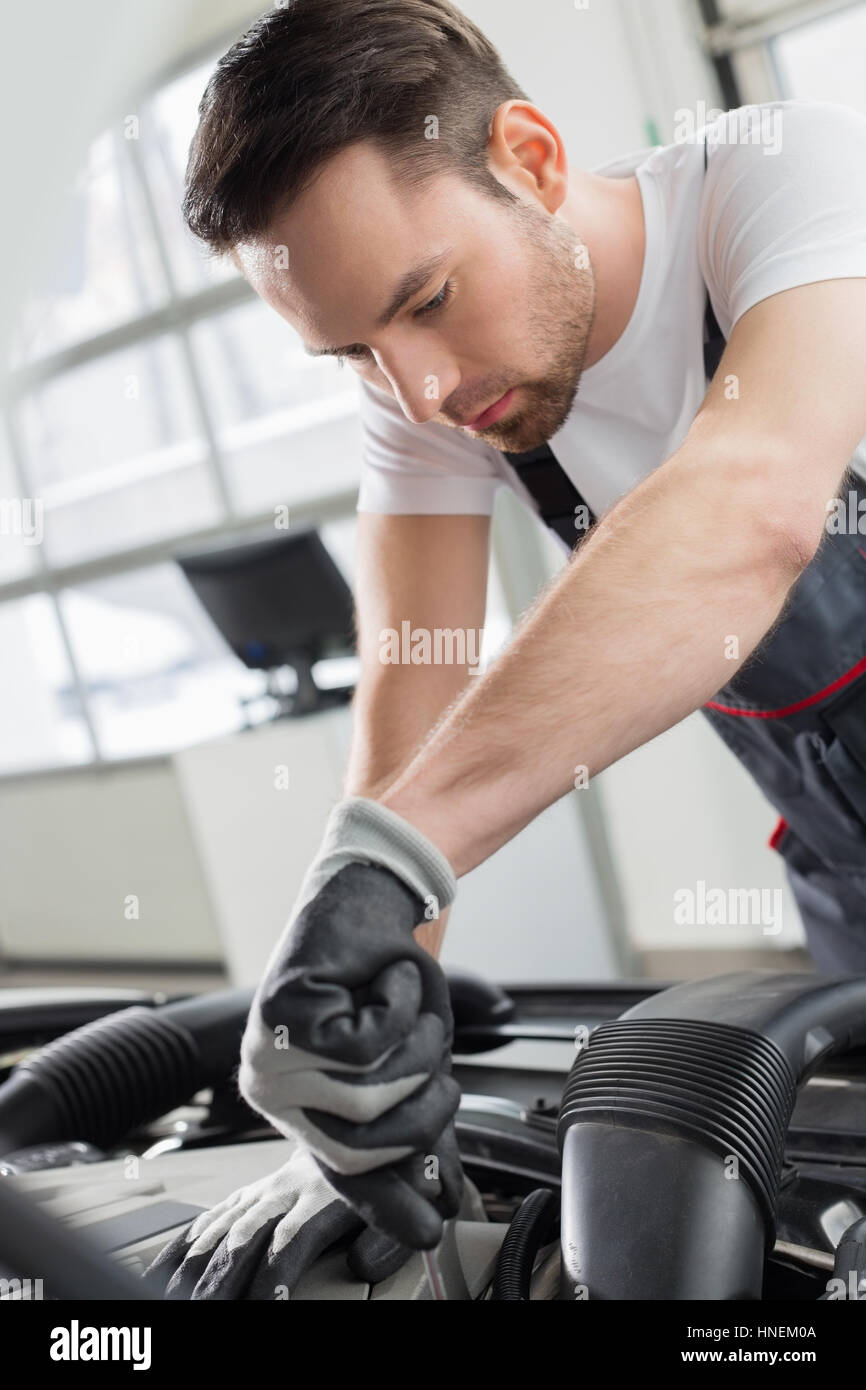 Young maintenance engineer repairing car in automobile store Stock
