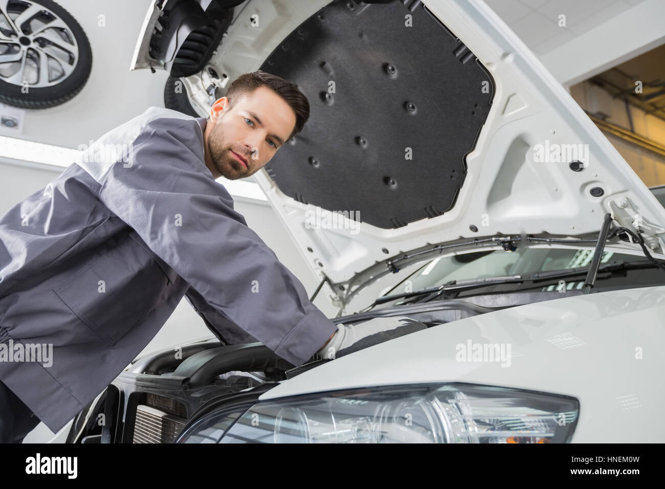Portrait of confident male repair worker repairing car engine in repair