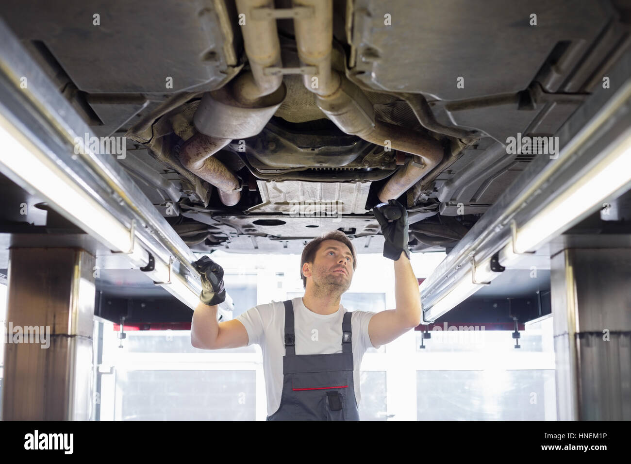 Mid adult male repair worker repairing car in workshop Stock Photo