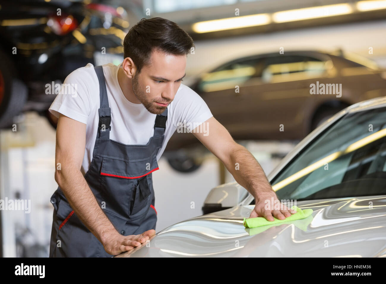 Young automobile mechanic cleaning car in repair shop Stock Photo