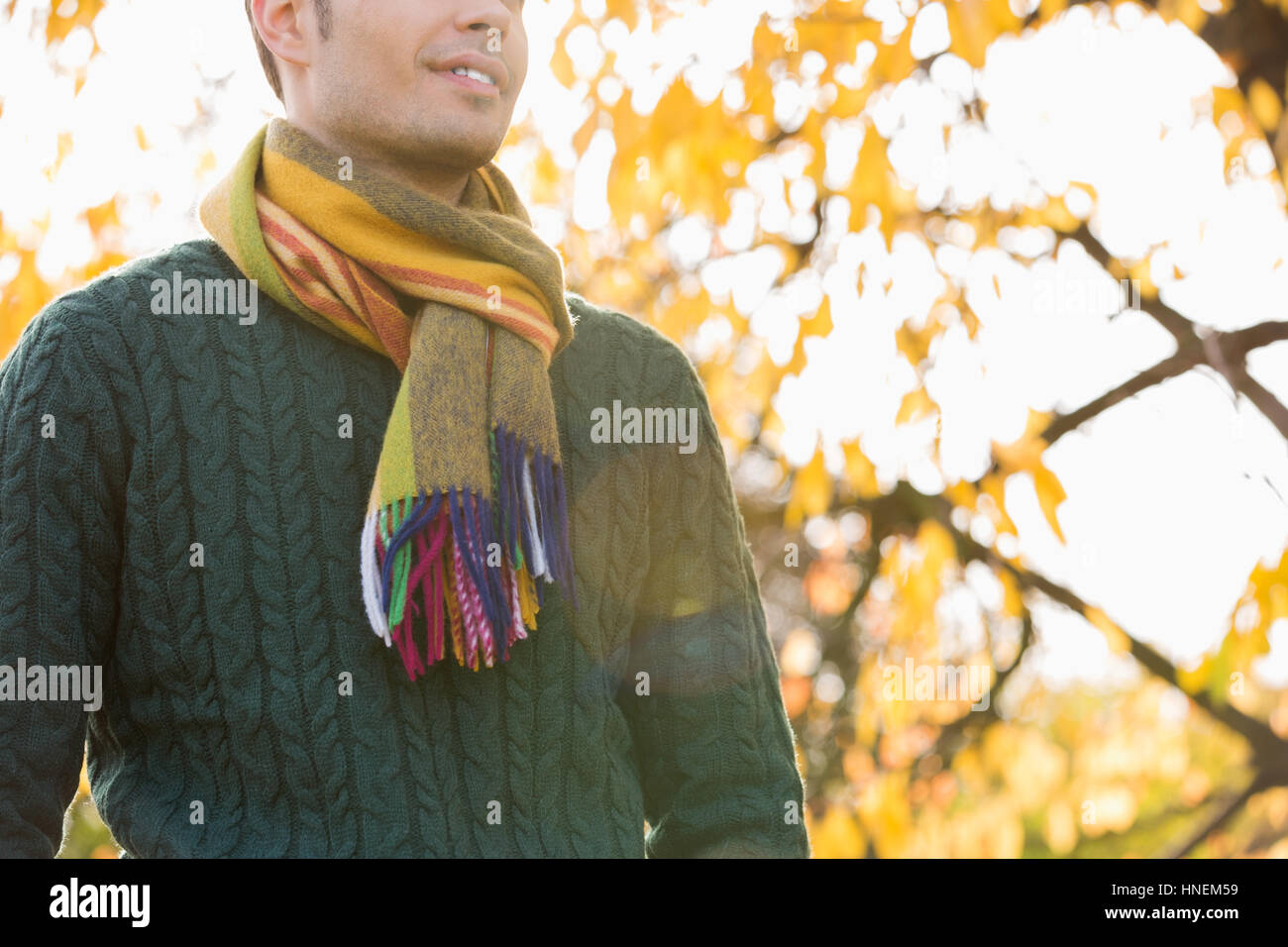 Midsection of man wearing sweater and muffler in park during autumn Stock Photo