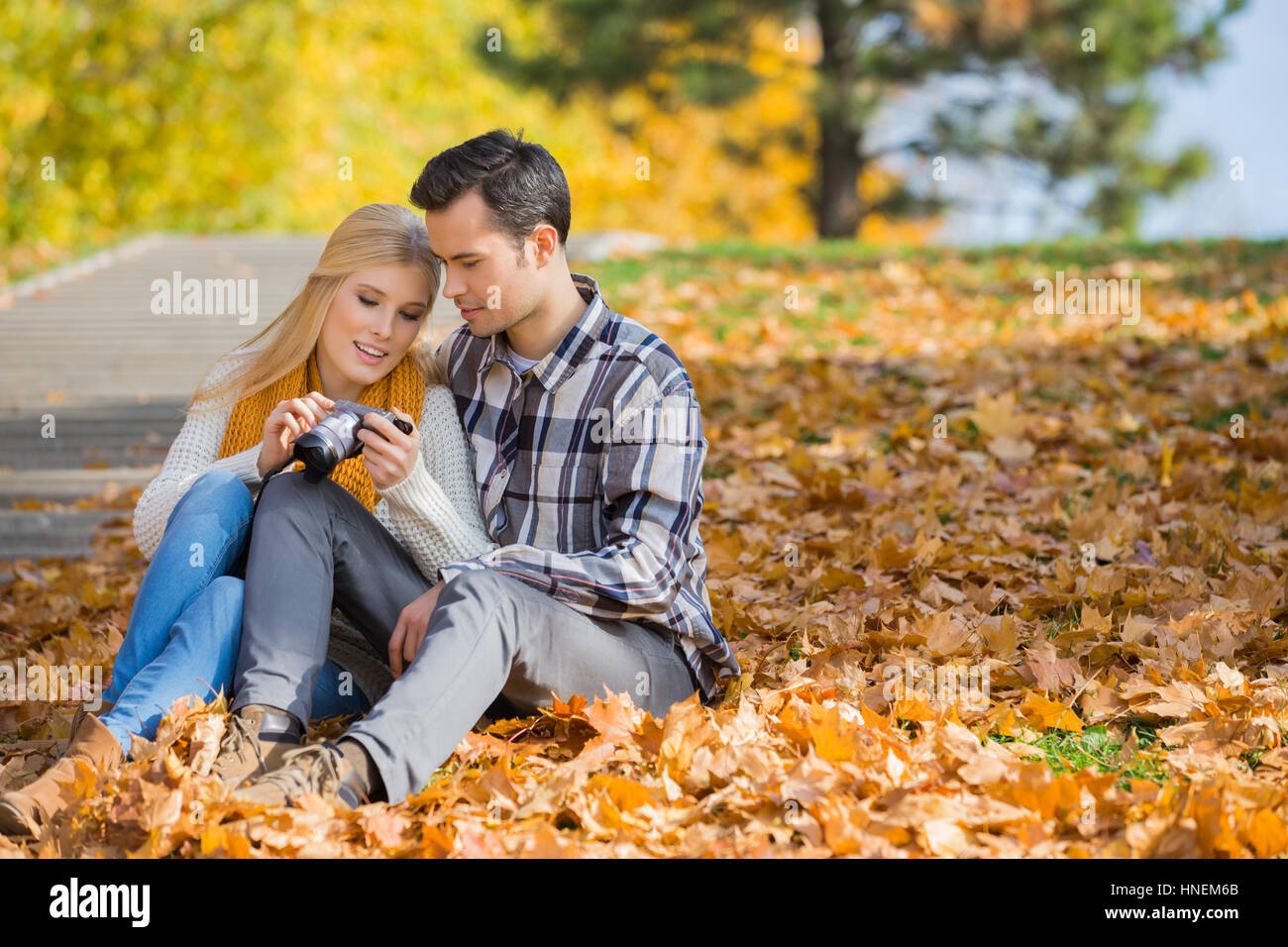 Couple looking at pictures on digital camera in park during autumn Stock Photo