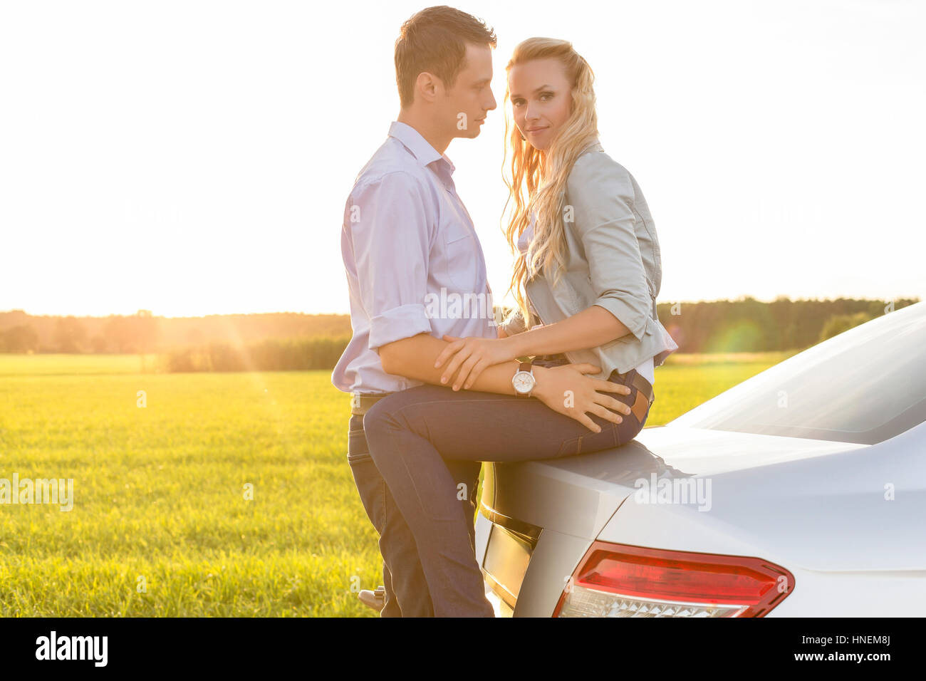 Side view of romantic young couple by car at countryside Stock Photo