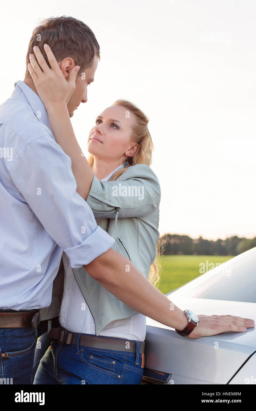 Side view of romantic young couple by car at countryside Stock Photo