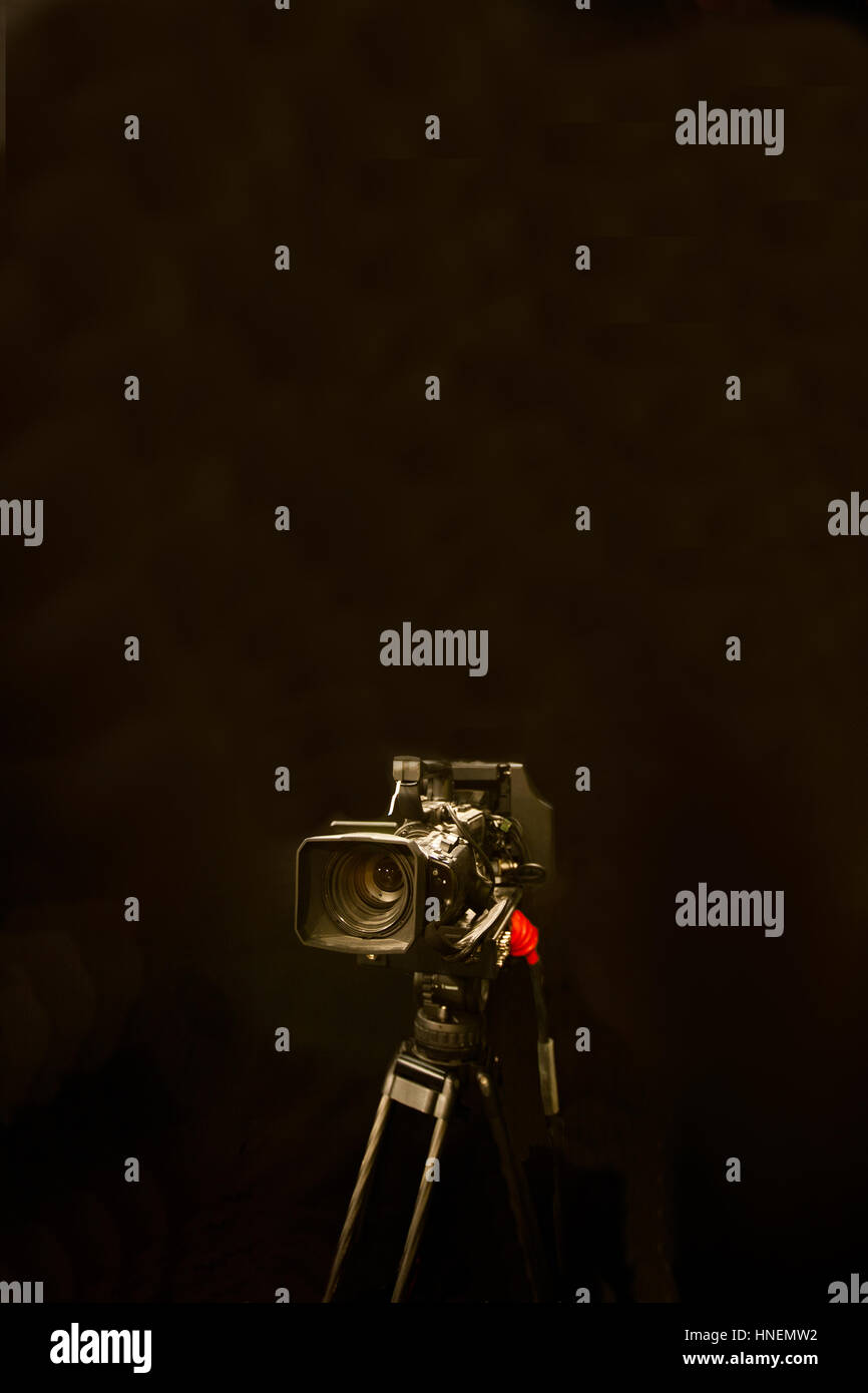 Digital camera and tripod against black background Stock Photo