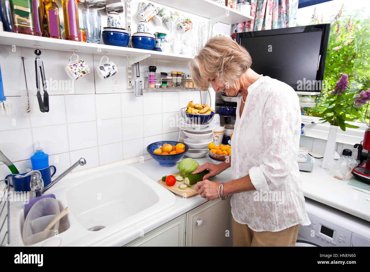 Senior woman chopping fresh vegetable while cooking at kitchen counter Stock Photo