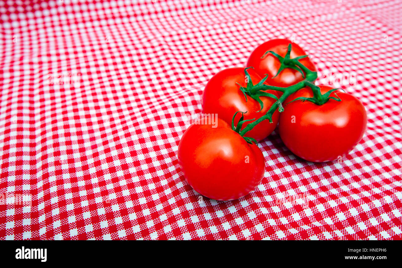 Red Vine tomatoes against red and white chequered cloth Stock Photo