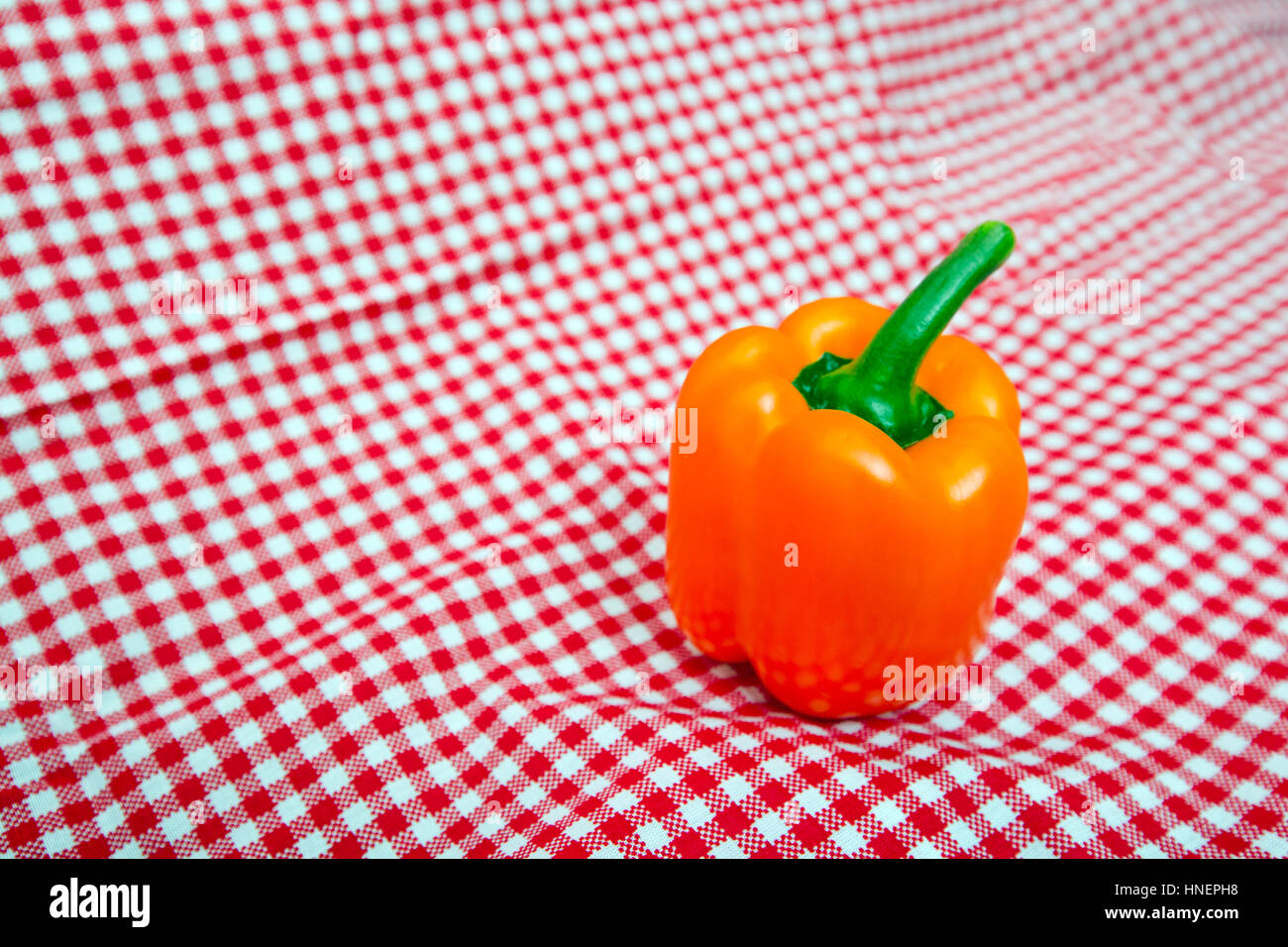 Orange Bell Pepper against red and white chequered cloth Stock Photo