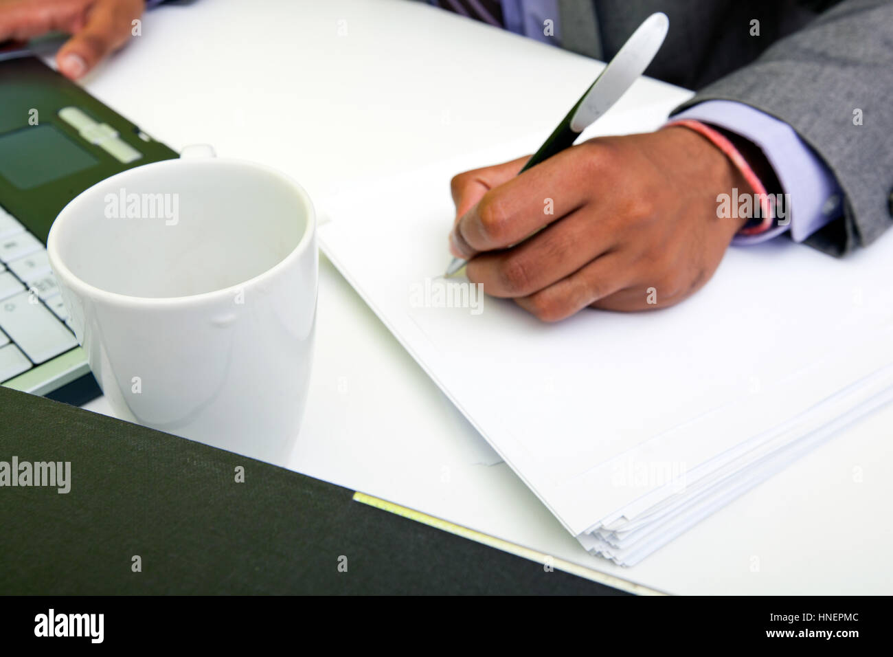 Close up of Indian mans hands writing on paper. Stock Photo