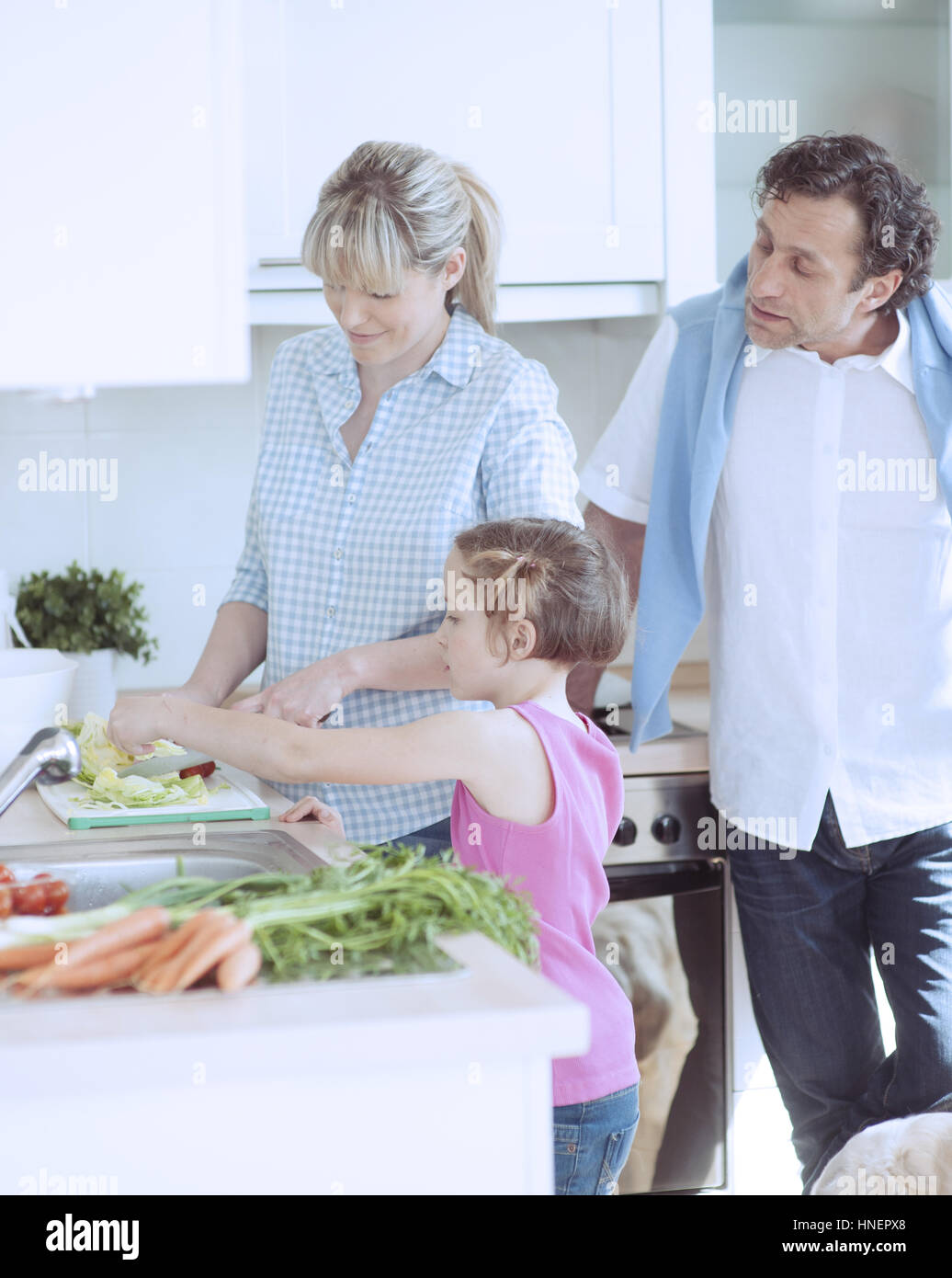 Family making a healthy salad in the kitchen Stock Photo