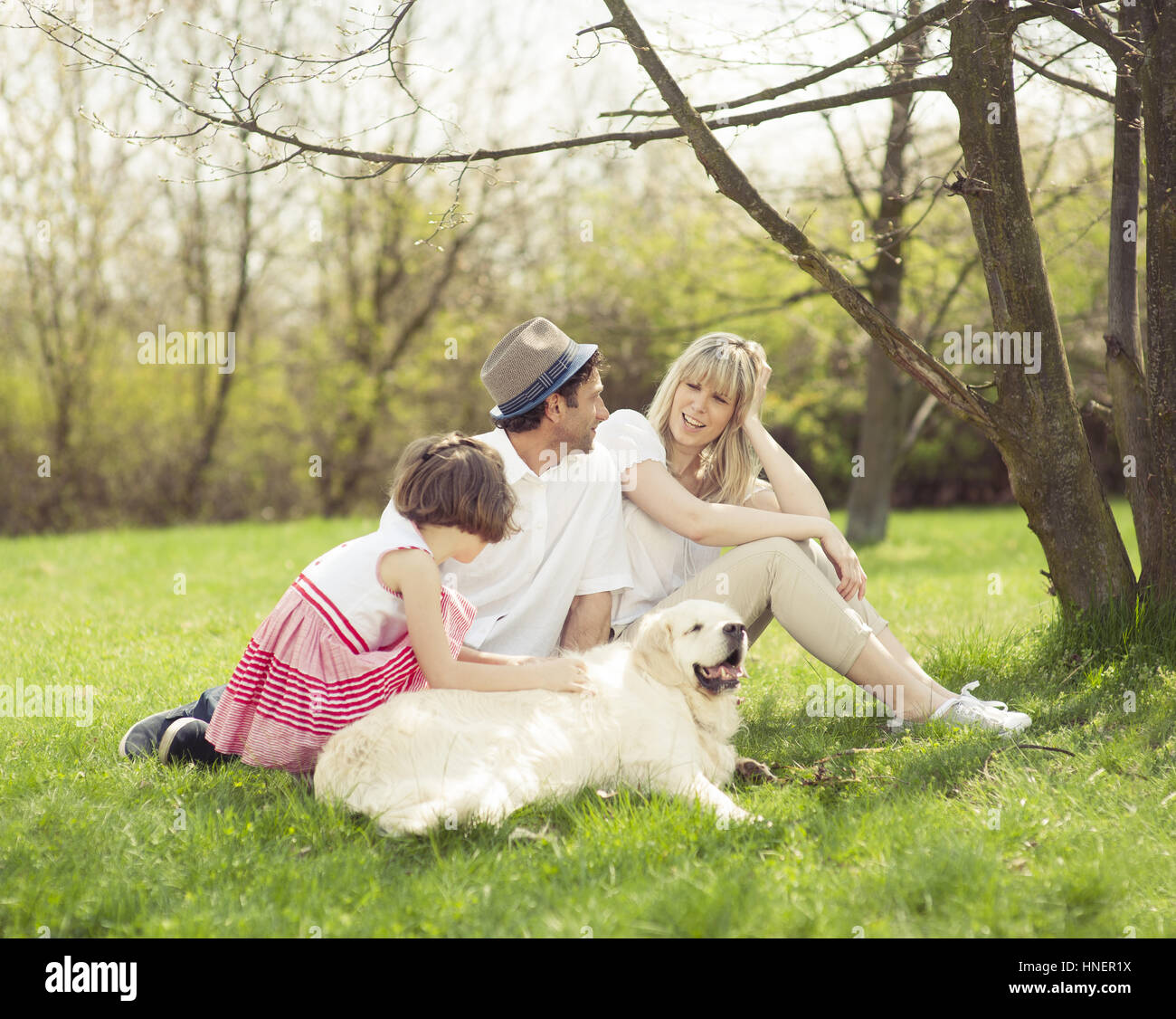 Family sitting in park with dog Stock Photo