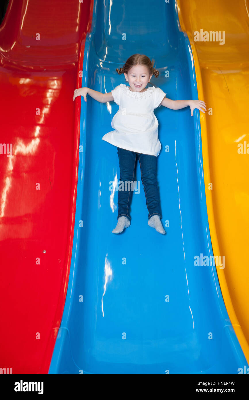 Young girl slides down colorful slide Stock Photo - Alamy