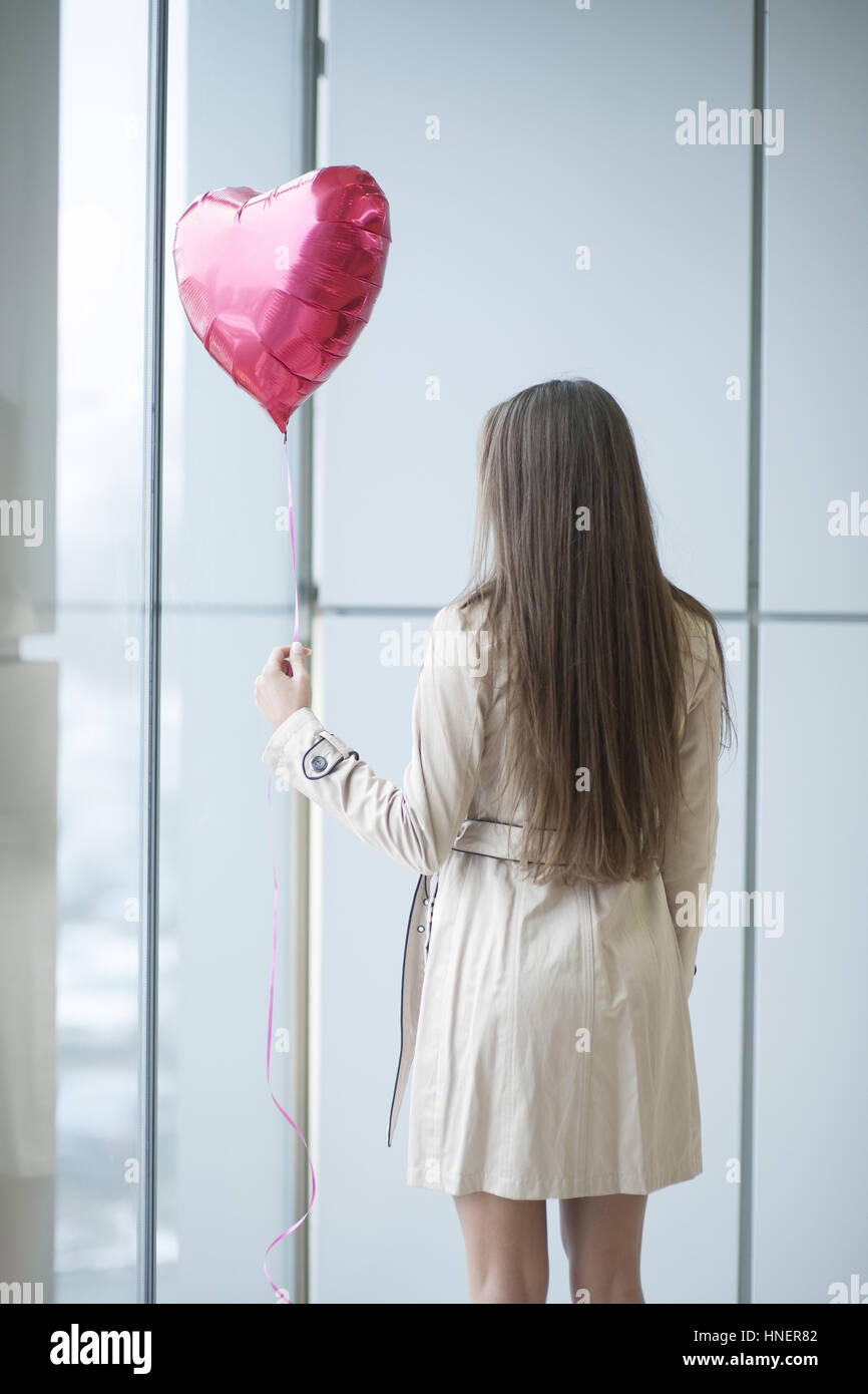 Woman with back to camera holding heart shaped balloon Stock Photo