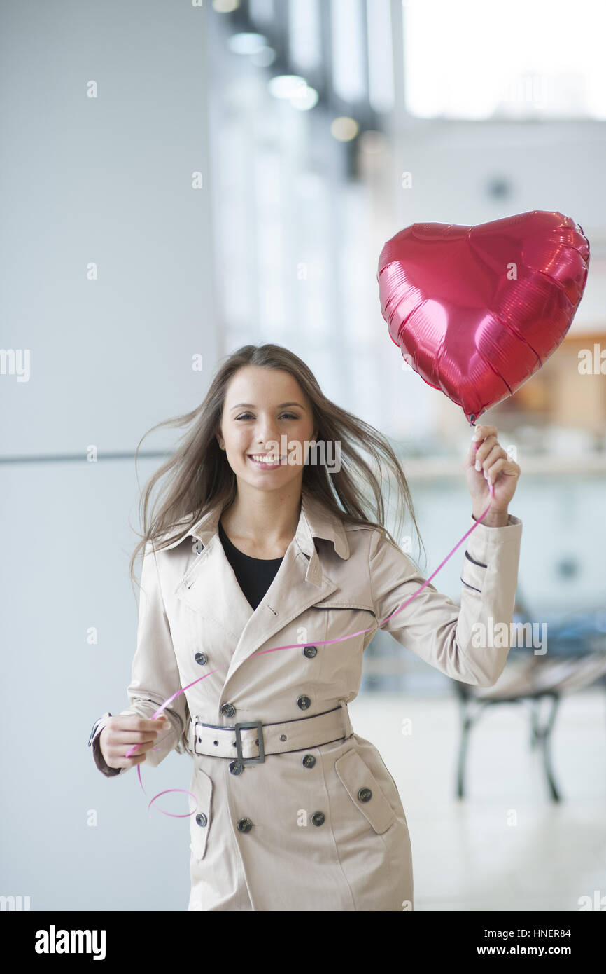 Businesswoman holding heart shaped balloon and smiling Stock Photo
