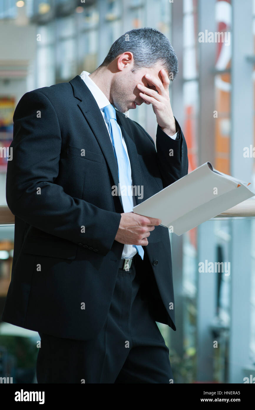 Business man reads document and covers face Stock Photo