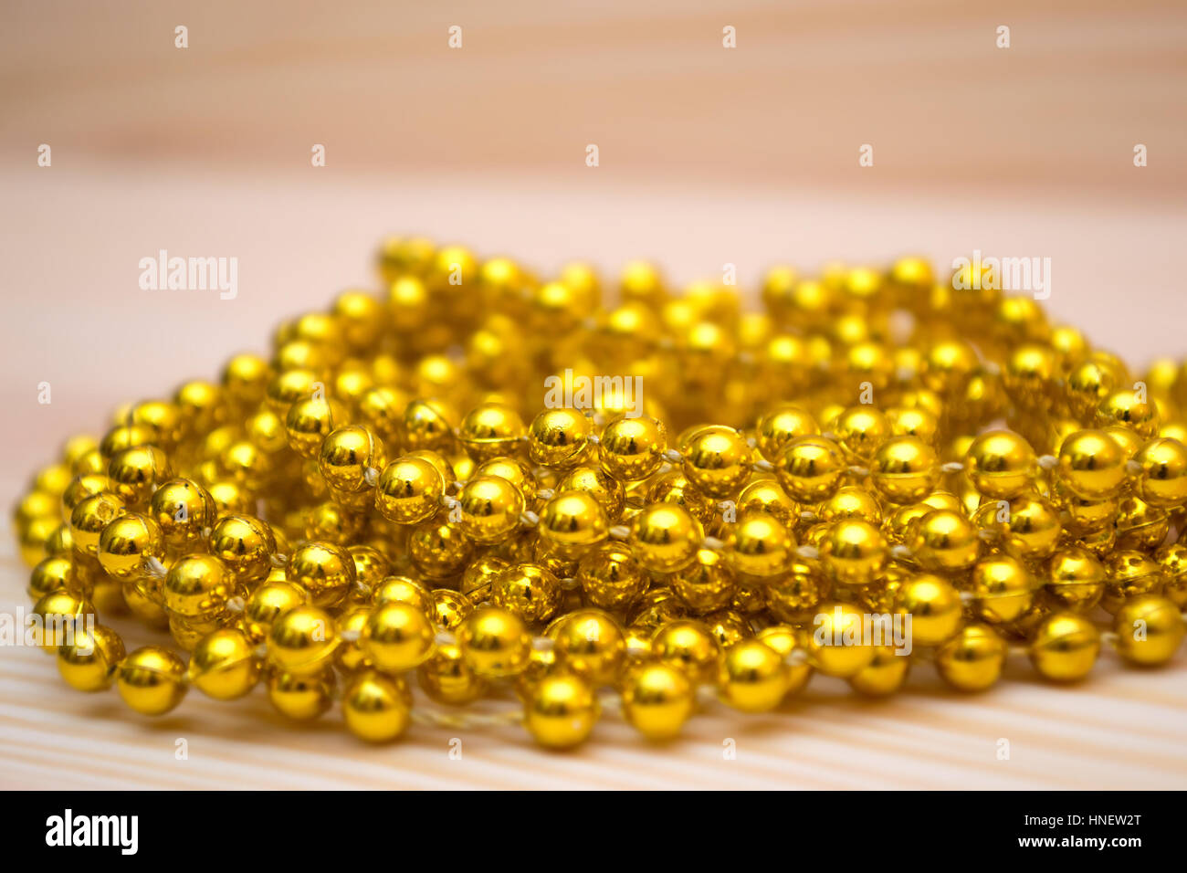 Golden beads on a wooden table. Gold Jewelry. Golden beads. Christmas decorations Stock Photo