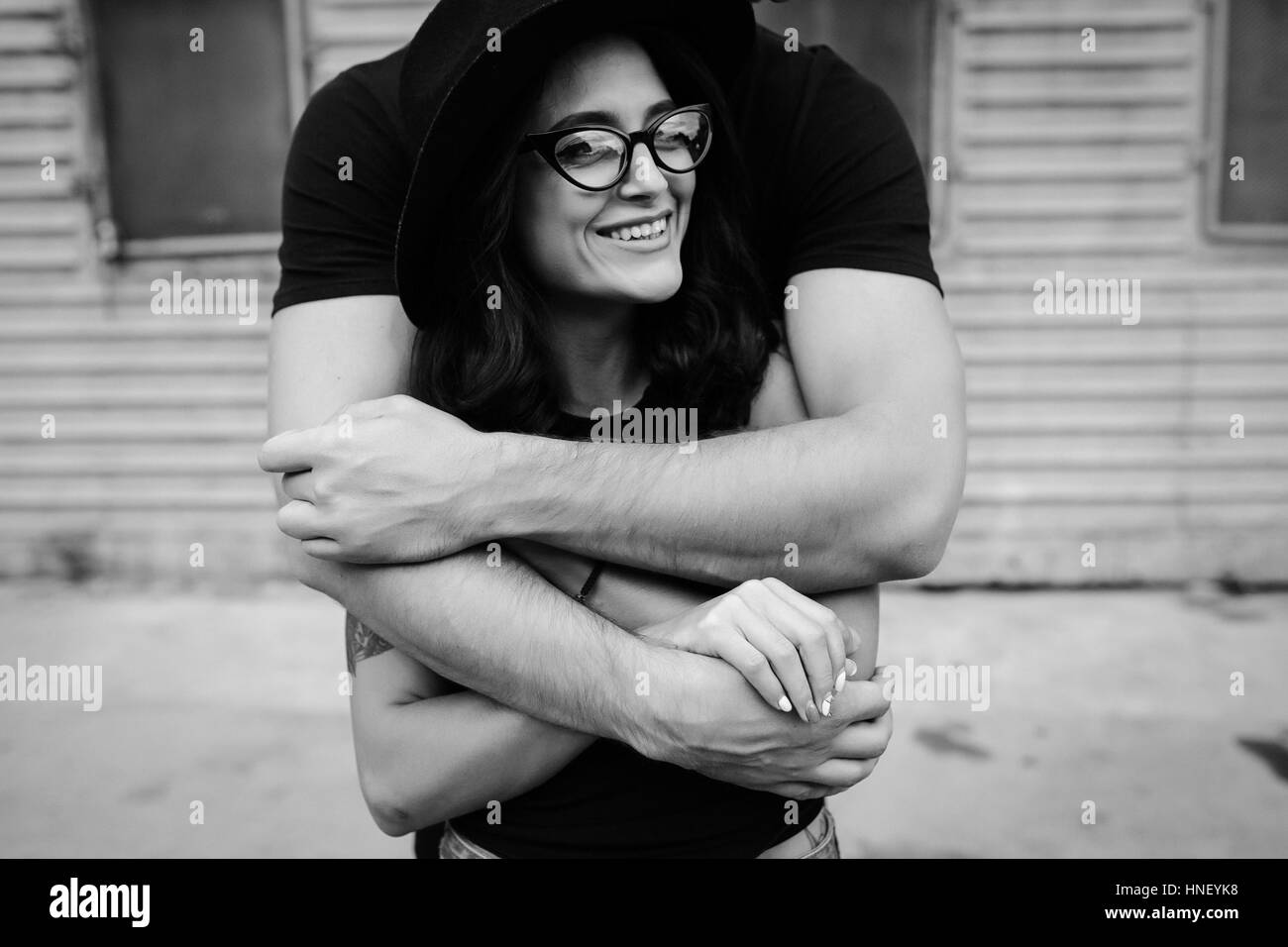 Guy hugging girlfriend from behind Black and White Stock Photos