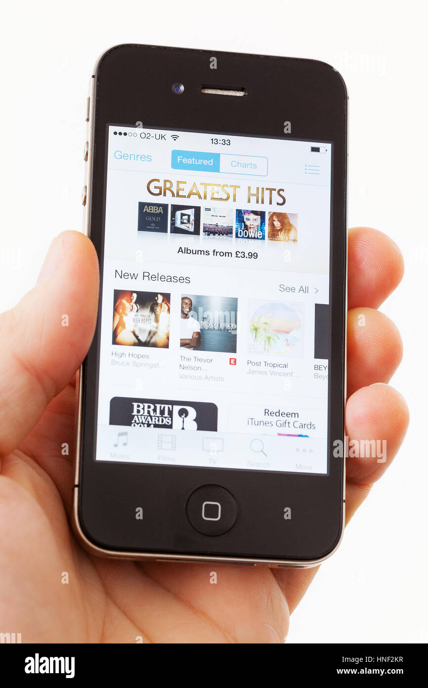 BATH, UK - JANUARY 15, 2014: A man's hand holding an Apple iPhone 4s which is displaying the front page of the Apple iTunes store. Shot in close-up ag Stock Photo