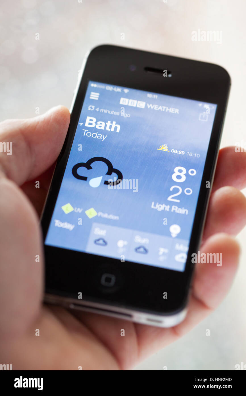 BATH, UK - MARCH 13, 2015 : Close-up of hand holding an Apple iPhone 4s displaying the weather forecast on the BBC Weather application. Shallow depth  Stock Photo