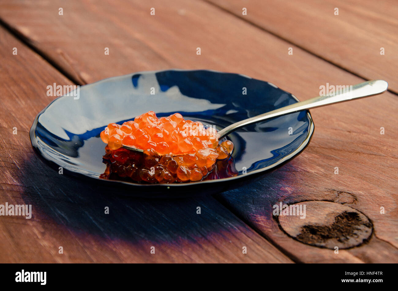 red caviar in a blue plate. wood planks Stock Photo