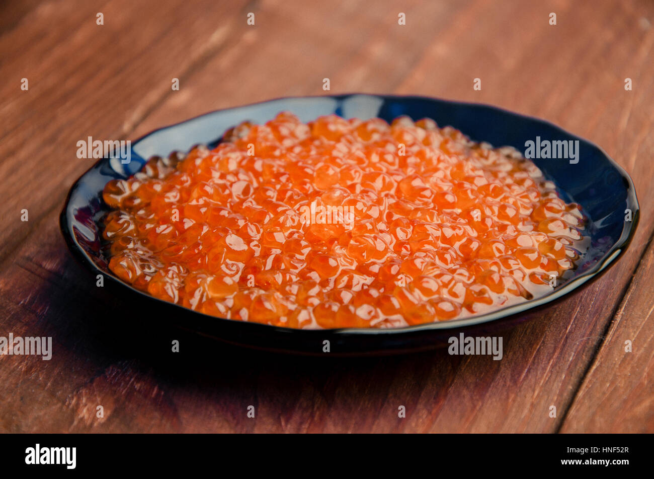 red caviar in a blue plate. wood planks Stock Photo