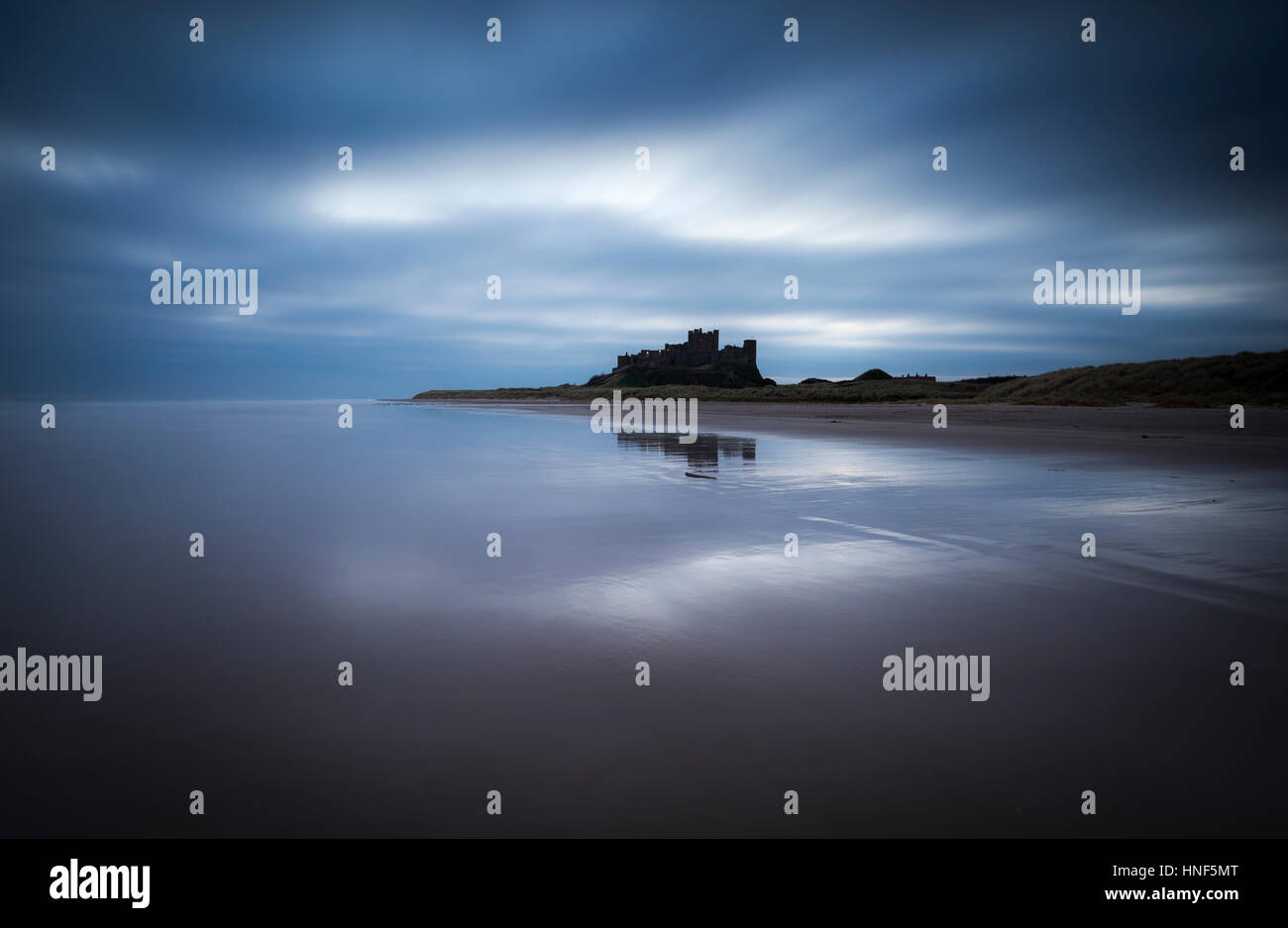 Bamburgh Castle on the Northumberland coast, captured during a long exposure photograph at dawn. Stock Photo