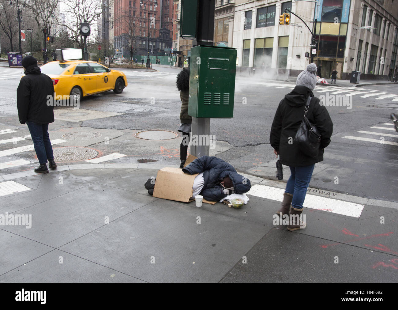 Homeless person prone on the sidewalk begging for money on Broadway in downtown Manhattan, NYC. Stock Photo