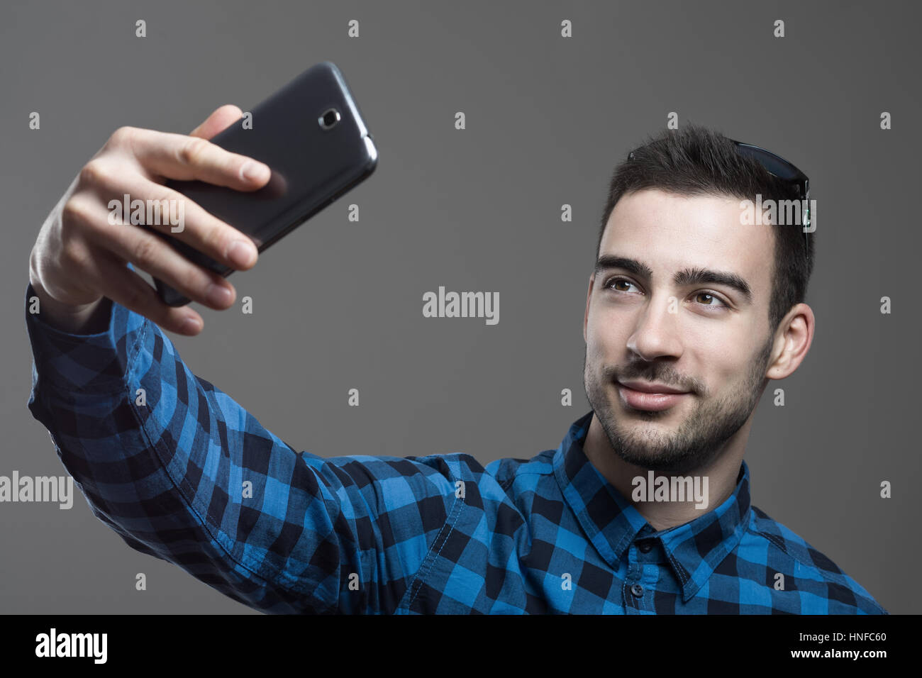  Confident flirty young man taking high angle selfie portrait over gray ...