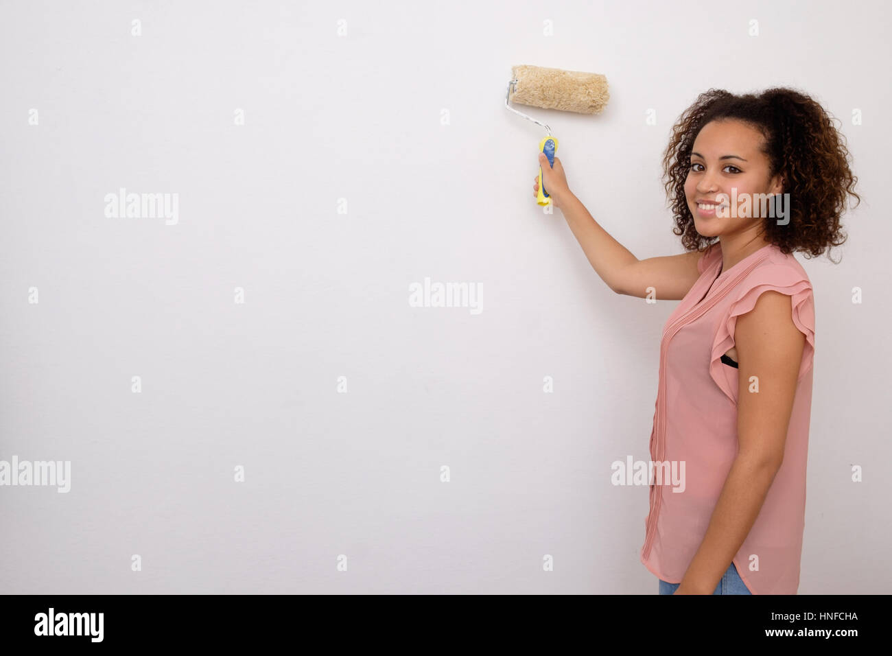 Woman painting the wall of her house Stock Photo