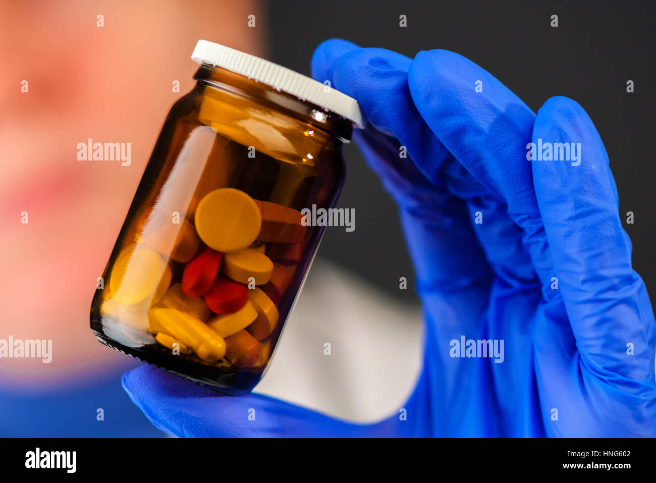 Female doctor holding unlabeled bottle of various pills and medication, prescription medicine and healthcare, selective focus Stock Photo