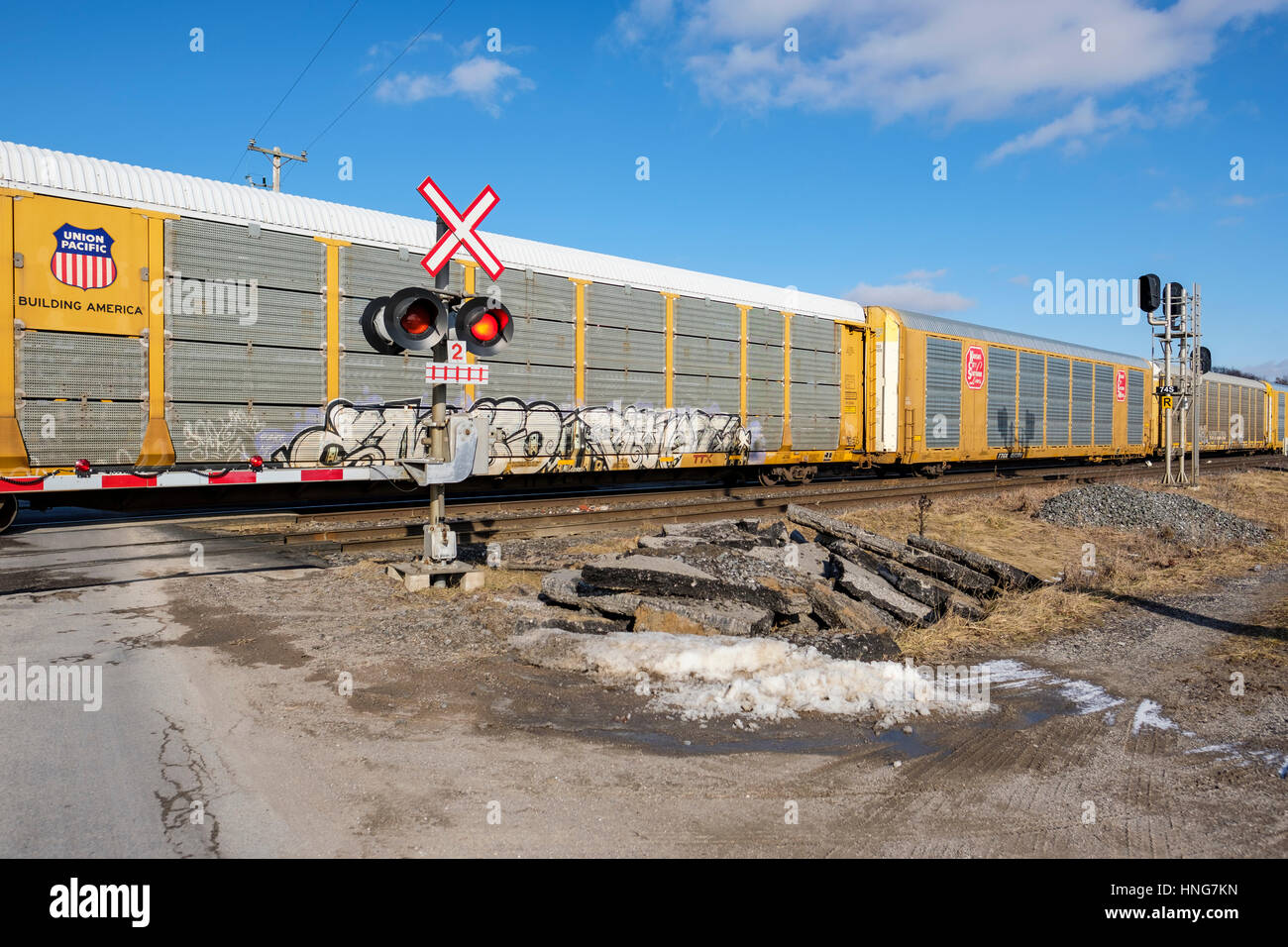 Freight cars passing through a railway level crossing during the day in Southwest Ontario, Canada. Stock Photo